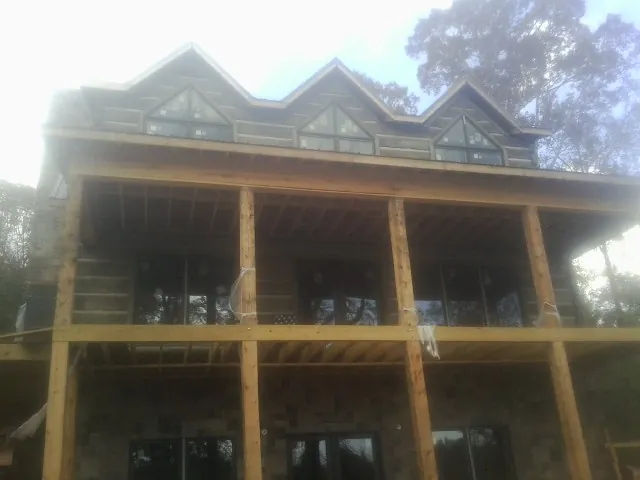 Dormers and porch framing on a large log home under construction — Roof Coating work by our crew in Redfield