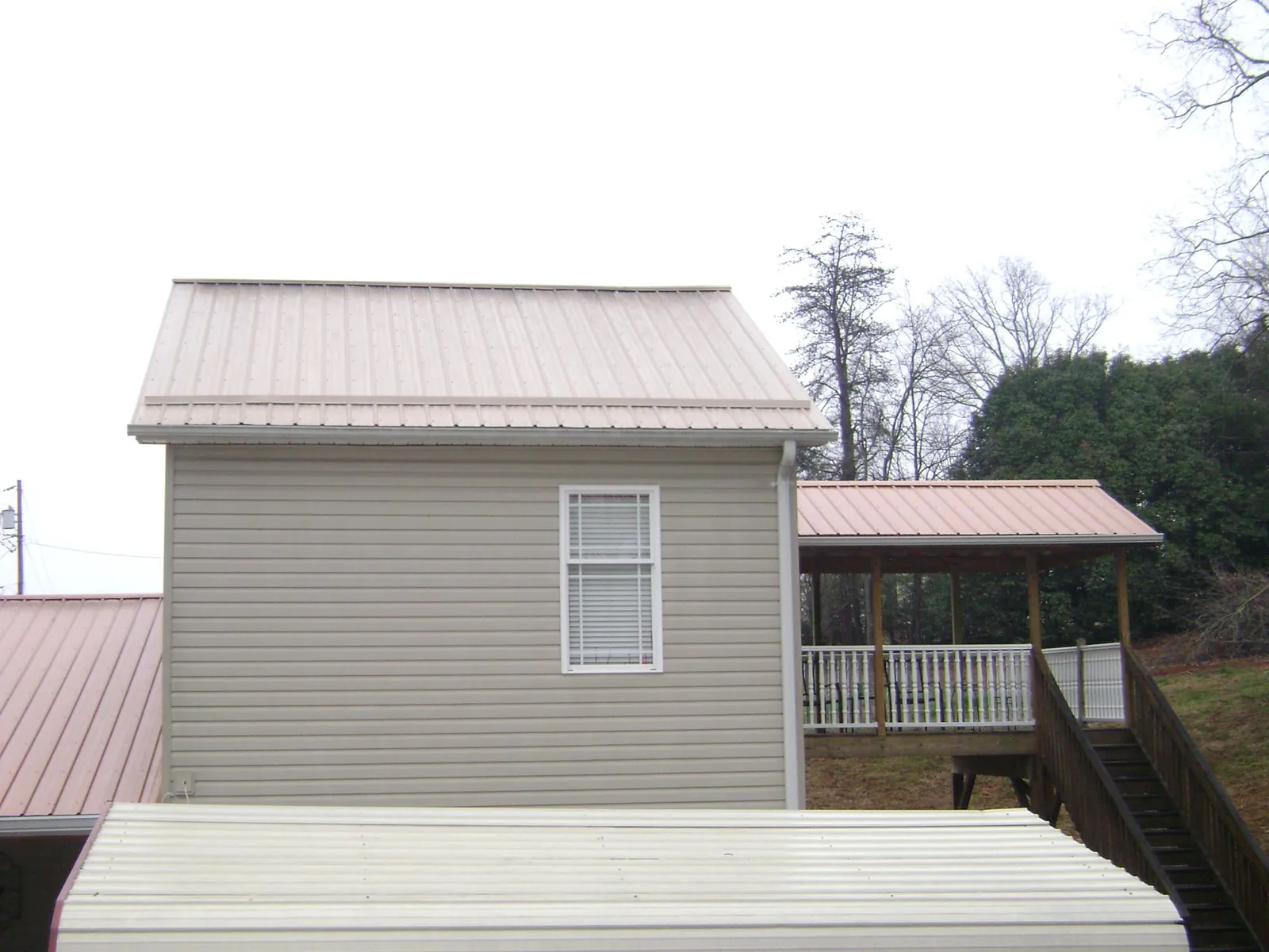 Tan metal roofs on a two story addition and attached porch, from a Roof Replacement job in Redfield